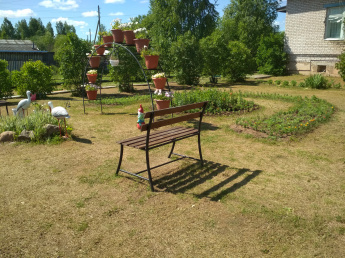 Оформлена зона для отдыха с цветочными клумбами и скамейками